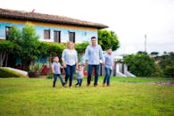 Áreas de Práctica Family of five enjoying a walk in a vibrant garden by a colorful house.